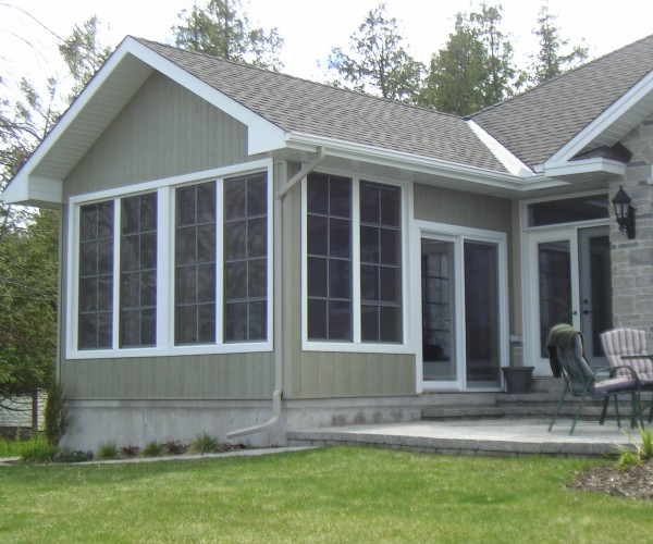 bungalow with large windows and concrete patio with furniture